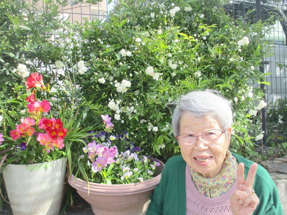 花の前でピースをする利用者さま