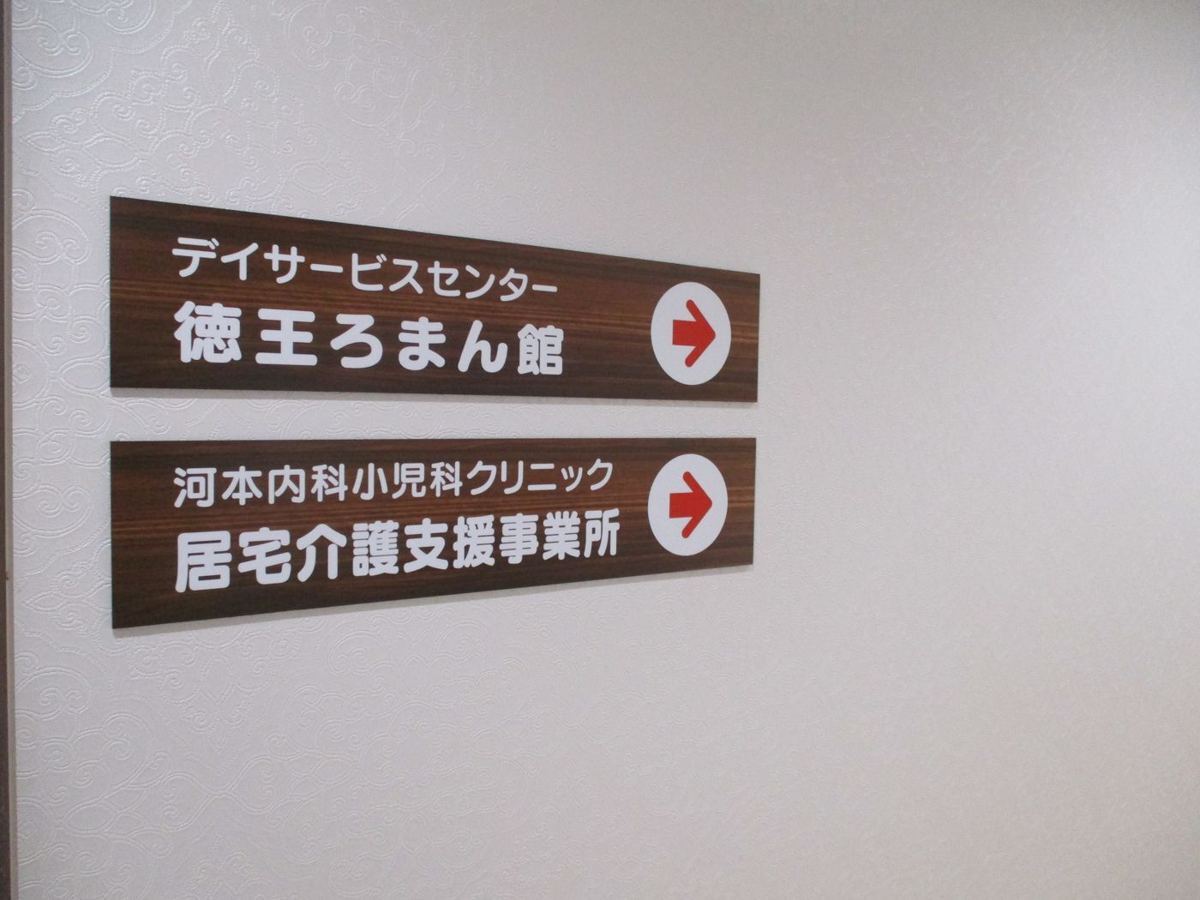 建物内の案内板。デイサービスセンター徳王ろまん館と、河本内科小児科クリニック居宅介護支援事業所の表示