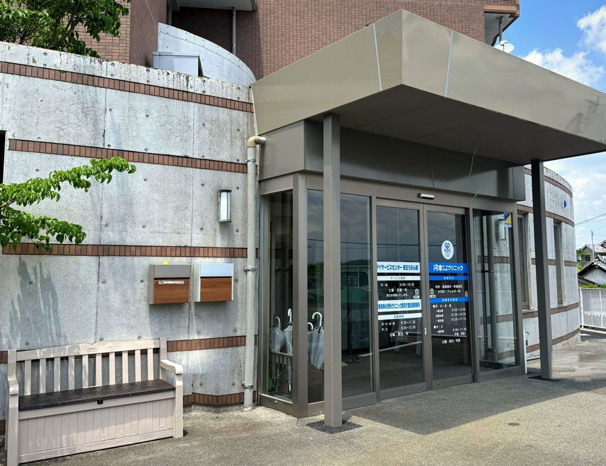建物の外観。ひさしのある入り口に、デイサービスセンター徳王ろまん館と河本内科小児科クリニックの表示